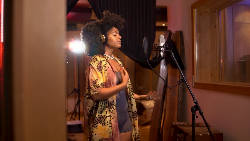 Female vocalist passionately recording her song in a soundproof studio, highlighting music production and creativity