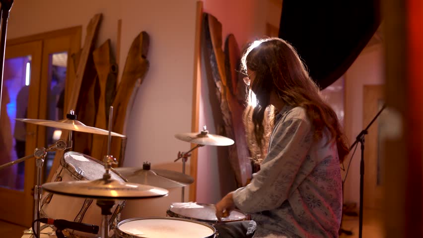 Talented young drummer energetically plays in a cozy studio, showcasing rhythmic skills and creativity. Warm lighting enhances the artistic atmosphere