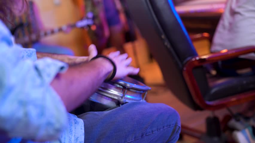 Musicians jamming together with percussion and guitar, creating a lively and dynamic atmosphere in a music studio setting