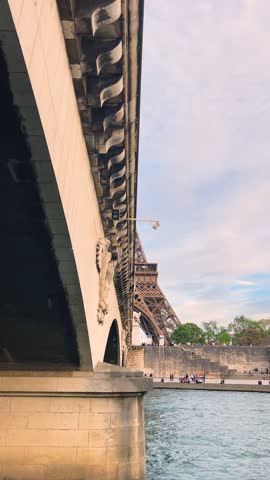 View of the left bank of the Seine River, the Eiffel Tower, boats sailing on the river, the Quai Jacques-Chirac embankment and Pont d'Iena, Jena Bridge spanning the River Seine of Paris, France.