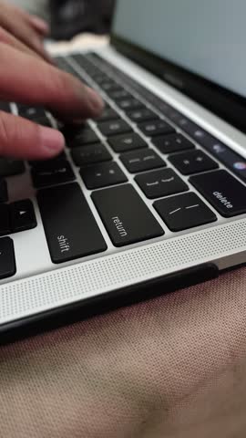 Close-up of male hands typing on a laptop and hitting the Enter key  (return key), symbolizing online activity or data input