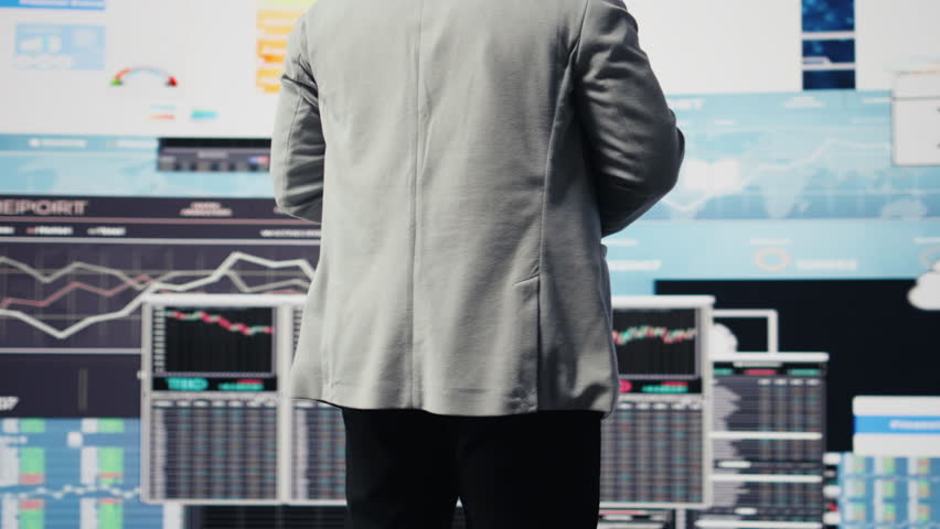 Black male entrepreneur reviews financial graphs and KPI models, reviewing business performance reports with strategic insight for fintech materials and forecasting tools. Management. Camera A.