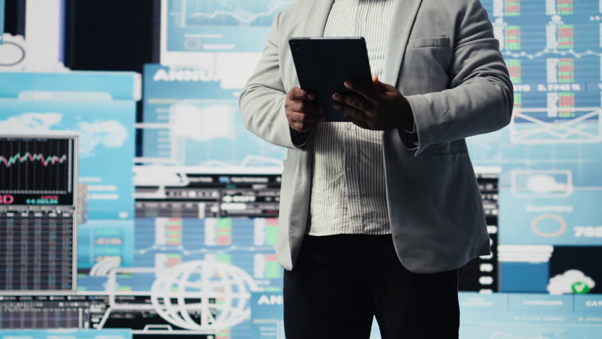 Black male entrepreneur reviews financial graphs and KPI models, reviewing business performance reports with strategic insight for fintech materials and forecasting tools. Management. Camera A. - Powered by Shutterstock - Get 15% off with code: PIKWIZARD15