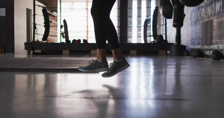 Woman bouncing on gym floor showing numeric overlay then swinging jump rope demonstrating endurance. Fitness, agility, cardio, workout, motivation, sport, active