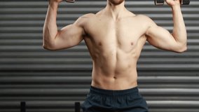 Shirtless man exhaling and pressing dumbbells overhead before wall with fitness icons tracking reps. Fitness, strength, workout, digital, technology, health, motivation - Powered by Shutterstock - Get 15% off with code: PIKWIZARD15