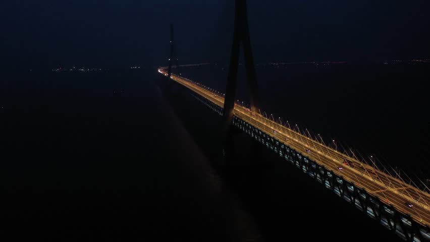 Experience the lively night traffic on Husutong Yangtze River Bridge, where streams of vehicles create bright trails against the dark backdrop of the river.