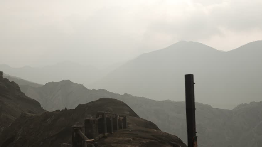 Misty high-altitude trail at Mount Bromo with peaks and rugged terrain fading into the haze, East Java, Indonesia.