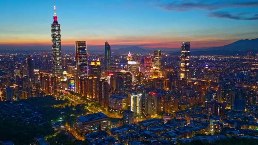 Aerial hyperlapse of Downtown Taipei at dusk, the vibrant capital city of Taiwan, with 101 Tower standing out amid skyscrapers in XinYi Commercial District and city lights dazzling under twilight sky