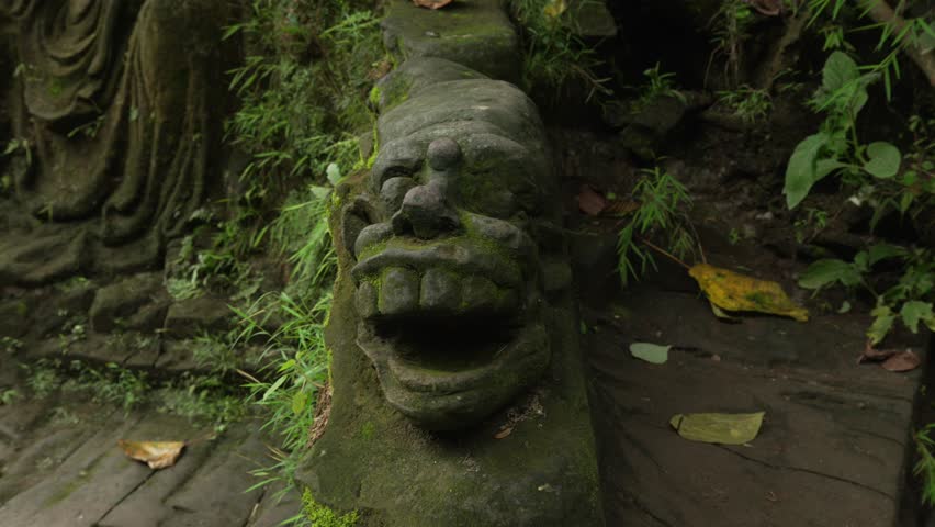 Face with large teeth carved in rock by Sumampan Waterfall hike trail, Bali, Indonesia.