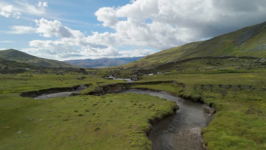 Aerial drone view of green river valley with curves and bright cloudy sky in ausangate peru