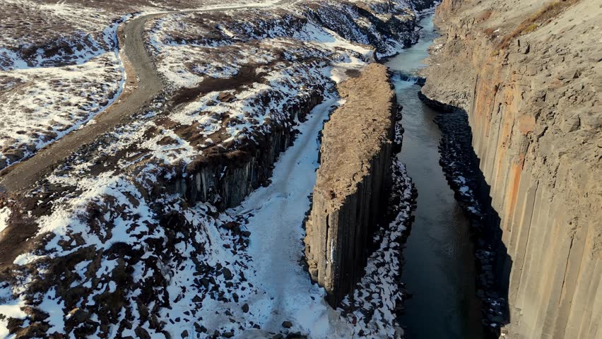 drone fly inside the Stuðlagil Canyon with scenic basalt column covered in snow during a sunny day of winter in the Jökuldalur valley in East Iceland