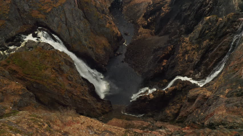 Majestic Voringsfossen waterfall with powerful cascades converging into pool within rugged gorge. Raw power and beauty of natural wonder in Norway