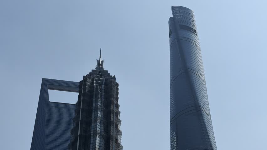 Modern skyscrapers Jin Mao Tower and Shanghai World Financial Center dominate the Shanghai skyline under a clear blue sky