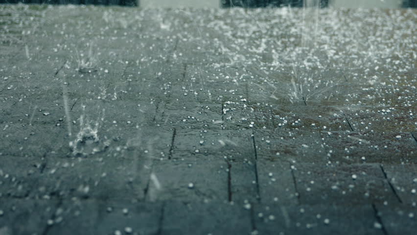 Intense hailstorm mixed with heavy rain hitting a roof covered with durable bitumen shingles, emphasizing strong weather impact and roofing protection. High quality 4k footage