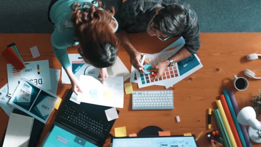 Top view of project manager looking at screen while designer writing idea. Close up of smart business team explain idea of logo design while designer choose theme while looking at palette. Symposium.
