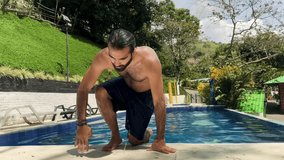 Colombian man with long hair and beard dripping water while stepping out of rural hotel pool on a sunny day, shirtless and surrounded by tropical nature in Risaralda - Powered by Shutterstock - Get 15% off with code: PIKWIZARD15
