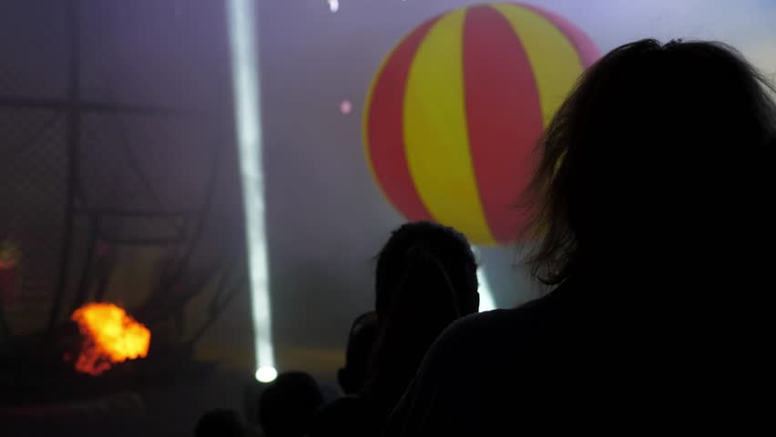 The silhouette of the audience in the circus at the performance, huge inflatable balls are thrown at the audience. Entertainment of guests in the circus between performances of artists. Circus show.