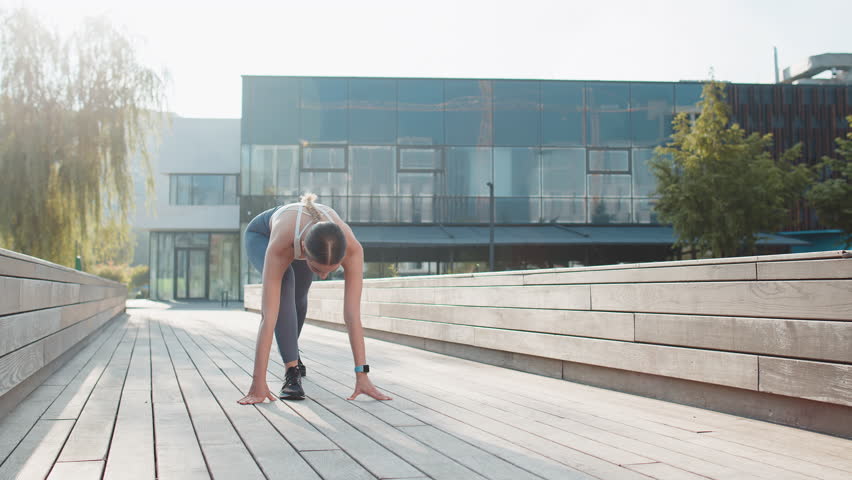 Athletic fit sport motivated runner girl training, preparing to run race marathon. Workout cardio in morning sunny park. Young woman jogger enjoying healthy lifestyle. Active sportswoman motivation.