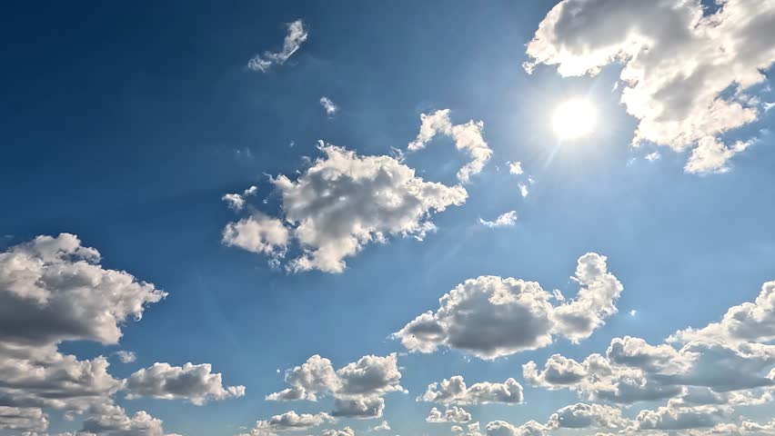 Bright Clouds in the Daylight Skies. 4K video (Ultra High Definition) of cloudscape and bright sun. Sky and clouds Timelapse. Sun shines through the clouds on the blue sky background. 