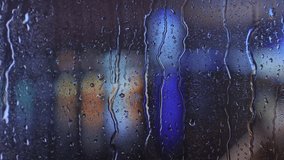 Raindrops dripping on a window pane with blurred multicolored city lights in the background at night. Bright bokeh effect creates a dreamy urban atmosphere. - Powered by Shutterstock - Get 15% off with code: PIKWIZARD15