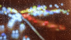 Raindrops dripping on a window pane with blurred multicolored city lights in the background at night. Bright bokeh effect creates a dreamy urban atmosphere. - Powered by Shutterstock - Get 15% off with code: PIKWIZARD15