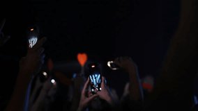 Smartphone wielding fans enthusiastically recording live music performance, capturing concert electric atmosphere with raised screens amid stage lighting and energetic crowd cheering - Powered by Shutterstock - Get 15% off with code: PIKWIZARD15