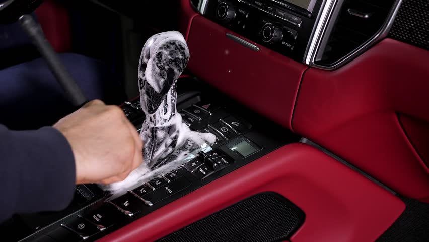 Cleaning the car interior with a brush. Auto detailing worker cleaning car interior, car detailing concept. Dust removal from the dashboard of the car with a brush.