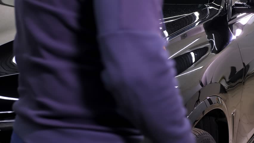 A man cleaning car with microfiber cloth, car detailing concept. Car service worker polishing car with microfiber cloth.