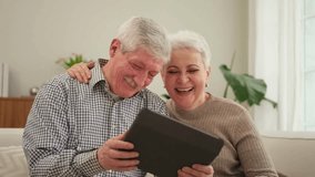 Senior old couple with tablet watching video online. Husband wife spending time together at home. Happy modern mature senior couple using tablet for family entertainment. Old people modern technology - Powered by Shutterstock - Get 15% off with code: PIKWIZARD15