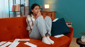 Indian young woman sitting on sofa looking at bills, receipts, praying with eyes upward, sincerely asking for help. Arabian girl experiencing hope desperation, emotionally praying hoping for a miracle - Powered by Shutterstock - Get 15% off with code: PIKWIZARD15