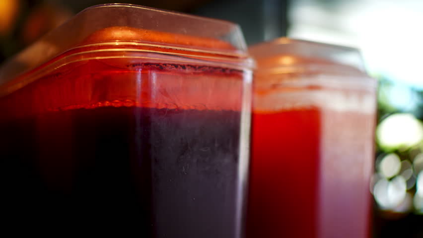 Cranberry and grapefruit juice dispensers standing side by side, showcasing vibrant colors and refreshing beverage options in commercial setting
