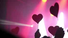 Concertgoers waving heart shaped cards, expressing deep emotional connection and passionate support during live music performance, radiating collective love and enthusiasm - Powered by Shutterstock - Get 15% off with code: PIKWIZARD15