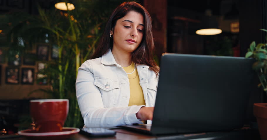 Woman, remote work and typing on laptop at cafe for research, writing story and feedback. Thinking, journalist and freelancer with digital, planning article and information for publication schedule
