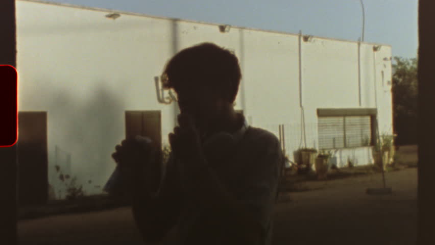 Filmed on super 8 film Vintage, retro style super 8 movie showing a teenager drinking and eating with a white industrial building in the background