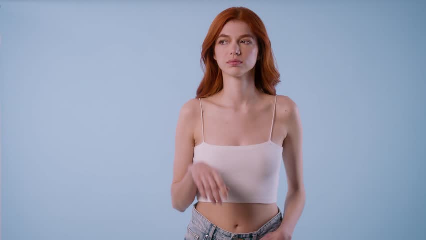 Young woman hears something off camera, reacts with a flirty smile, then laughs joyfully toward the viewer.