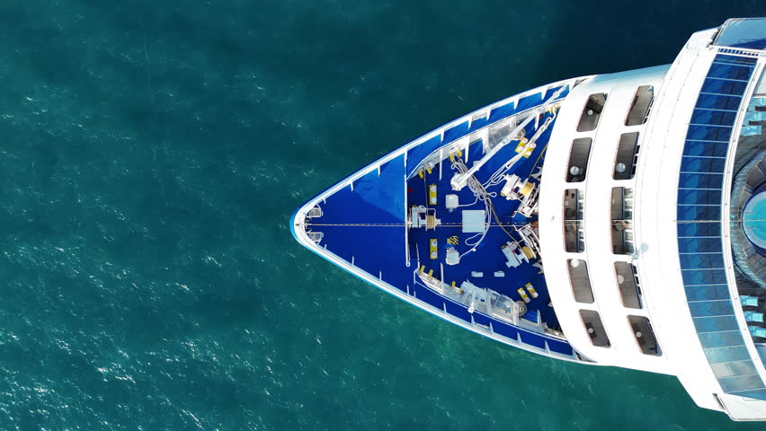 Aerial top view of a luxury cruise ship sailing through deep blue ocean water. Vibrant deck design with pools, sun loungers, and activity zones, ideal for travel, vacation, and maritime lifestyle