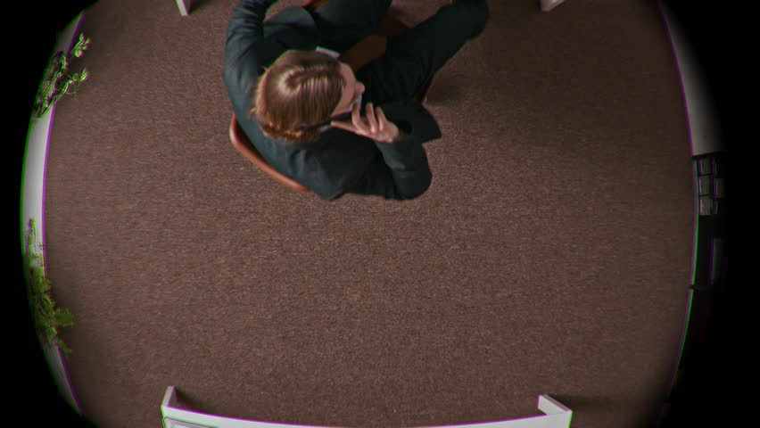 Fish eye directly above shot of Caucasian young male boss holding papers with contract standing up from office chair during important phone call