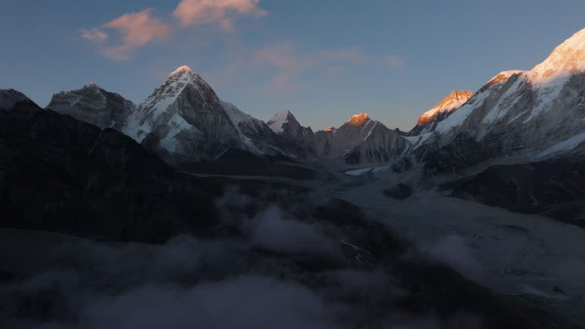 Aerial View of Snow-Capped Mountains in Nepal at Dawn, Highlighting the Majestic Glacier Valley and Misty Clouds Below