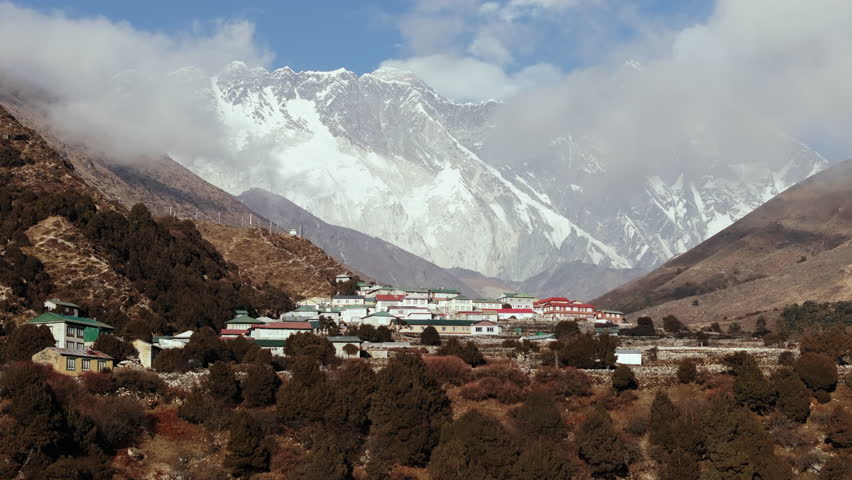 Aerial perspective of a tranquil mountain hamlet in Nepal, featuring rustic buildings and grand snow peaks