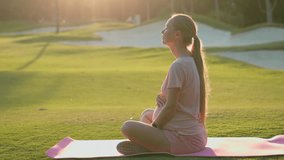 Pregnant woman meditating on green field at sunrise. Mindfulness, inner peace, healthy pregnancy and prenatal wellness concept for yoga retreats, maternity blogs and health campaigns. Slowmotion video - Powered by Shutterstock - Get 15% off with code: PIKWIZARD15