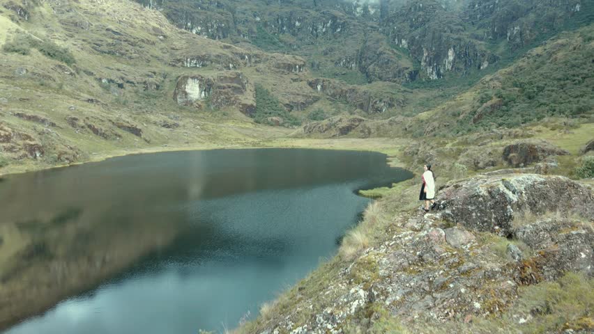 Peasant woman on a rock on the shore of a lagoon (Laguna Linda, Pachitea, Peru), peace, travel concept, tourism
