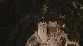 aerial drone view above castle. impregnable incredible ancient historical castle fortress building on top of mountain in middle forest flag Switzerland on spire. Swiss flag red background white cross - Powered by Shutterstock - Get 15% off with code: PIKWIZARD15