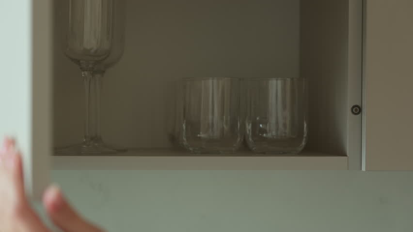 Woman closing kitchen cabinet. Modern furniture at home, storage design