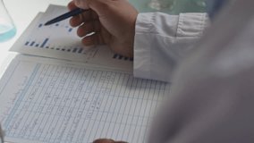 Hands of unrecognizable male scientist analyzing bar charts and taking notes on laboratory report during research work. Close-up view - Powered by Shutterstock - Get 15% off with code: PIKWIZARD15