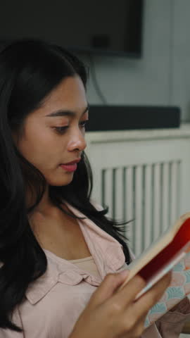 Young woman reading book, relaxing indoors