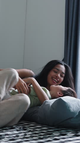 Authentic family moments of a mother enjoying playtime with her baby son on a bed