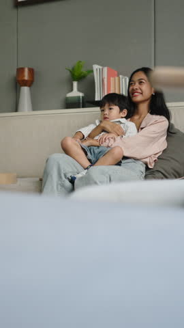 Mother hugging young son during family tv time at home