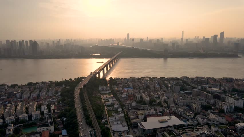 Sunset lights reflect on the Yangtze River, showcasing a vibrant cityscape. Bridges connect the two sides, creating a stunning silhouette against the colorful sky.