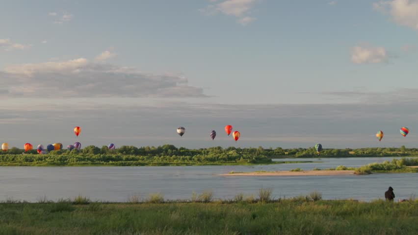 Hot air balloon festival over the river, many different balloons flying, hot air balloon fiesta