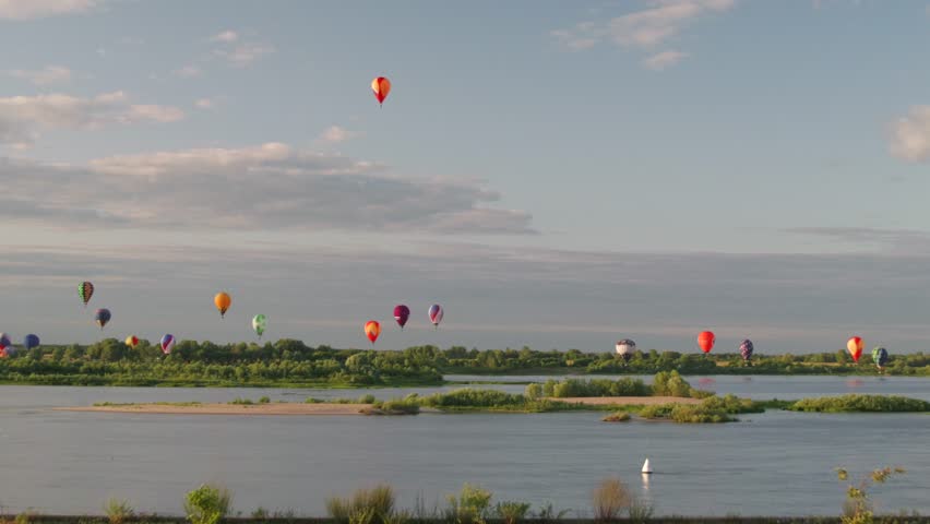 Hot air balloon festival over the river, many different balloons flying, hot air balloon fiesta